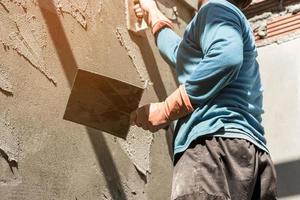 estucador concreto trabalhador às parede do casa construção foto