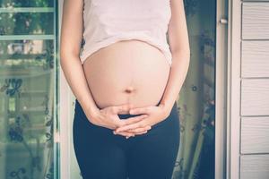 fechar acima mão grávida mulher segurando dela barriga foto