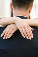 a da noiva mãos com a noivado anel em dela dedo abraço a noivo de a pescoço foto