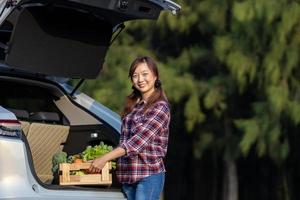 agricultor asiático está entregando colheita fresca de caixa de vegetais orgânicos no carro do cliente para apoiar o conceito de negócios locais foto