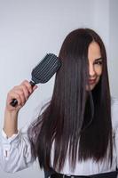 jovem penteando seus longos cabelos escuros com um pente em um salão de beleza foto
