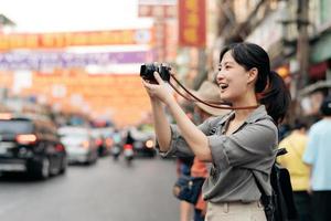 jovem ásia mulher mochila viajante desfrutando China Cidade rua Comida mercado dentro Bangkok, tailândia. viajante verificação Fora lado ruas. foto