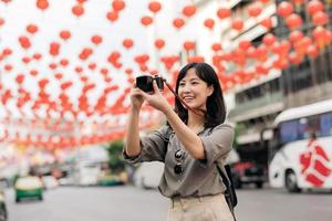 jovem ásia mulher mochila viajante desfrutando China Cidade rua Comida mercado dentro Bangkok, tailândia. viajante verificação Fora lado ruas. foto