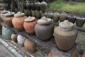 vários potes antigos de terracota com tampas de madeira no topo. foto