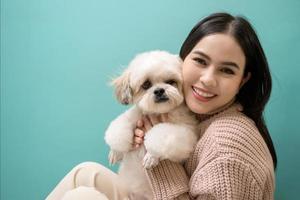 retrato do jovem lindo mulher Beijos e abraços dela cachorro sobre verde fundo. foto