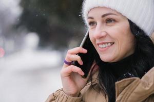 ampla retrato do uma jovem mulher com uma telefone em a rua dentro inverno foto
