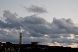 farol às pôr do sol em nublado céu background. patético, Chipre foto