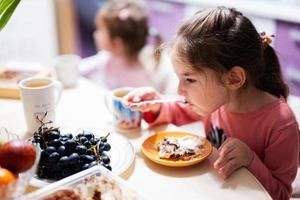 crianças comer frutas e sobremesas, beber chá às casa dentro a tarde cozinha. foto