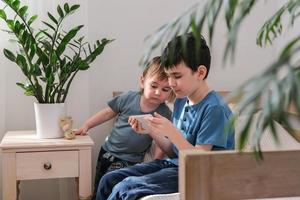 dois pequeno irmãos alegremente assistindo desenhos animados juntos em uma Smartphone. crianças e gadget conceito foto