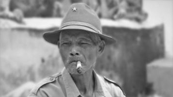 velho homem fumar uma cigarro, emitindo fumaça, com borrão fundo foto