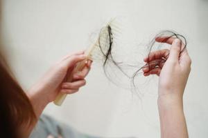 mulher asiática tem problema com perda de cabelo comprido anexado na mão. foto