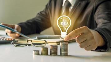 empresário segurando uma lâmpada, ideias na mesa, ideias para finanças, investimentos e administração de um negócio de sucesso foto