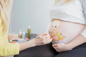 Maquiagem artista tintas uma criança em a barriga foto