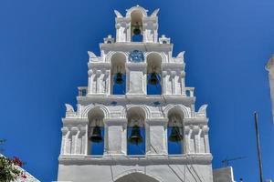 uma típica calçada portuguesa rua com a arqueado Sino torre dentro a tradicional Vila do megalochori dentro santorini, Grécia. foto