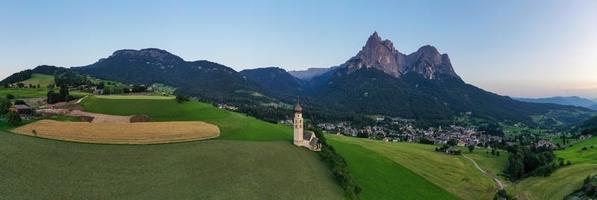 st. valentin kastelruth Vila Igreja dentro a verão dentro a dolomite Alpes. surpreendente panorama com pequeno capela em ensolarado Prado e petz pico às kastelruth comuna. dolomitas, sul Tirol, Itália foto