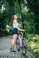 retrato de uma mulher com uma bicicleta rosa no parque foto