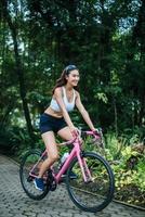 retrato de uma mulher com uma bicicleta rosa no parque foto