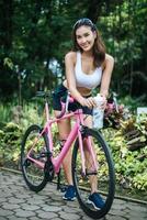 retrato de uma mulher com uma bicicleta rosa no parque foto
