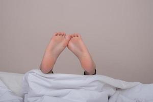 pés descalços da mulher na cama foto