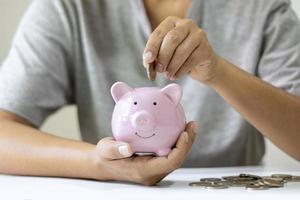 mulheres colocam moedas em um cofrinho rosa e economizam dinheiro para planejar suas futuras ideias de fundos de aposentadoria foto