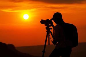silhueta de uma pessoa asiática tirando uma foto ao pôr do sol