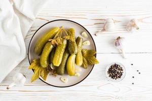 em conserva pepinos em uma prato e ingredientes para cozinhando em uma de madeira mesa. caseiro aperitivos. topo Visão foto