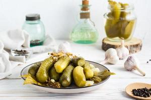 em conserva pepinos em uma prato e ingredientes para cozinhando em uma de madeira mesa. caseiro aperitivos. foto