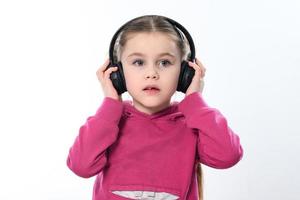 uma criança com fones de ouvido em uma branco fundo, uma alegre e lindo menina com fones de ouvido. foto