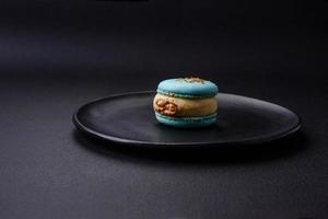 lindo saboroso macaron com o preenchimento e fruta sabor em uma Preto prato foto