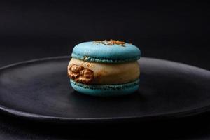 lindo saboroso macaron com o preenchimento e fruta sabor em uma Preto prato foto