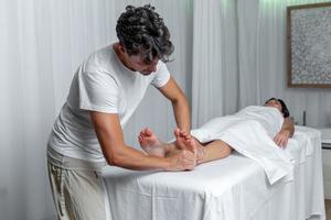 masculino massagista aplicando pressão para pé do mulher dentro reflexologia massagem às spa foto