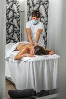 relaxado mulher recebendo uma tratamento do costas massagem de uma masculino massagista dentro spa Centro foto