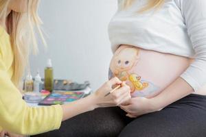 Maquiagem artista desenhar uma criança pequena em a barriga foto