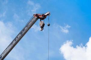 Móvel guindaste estrondo com gancho suspensão de fio cabo fundo azul céu, fechar acima foto