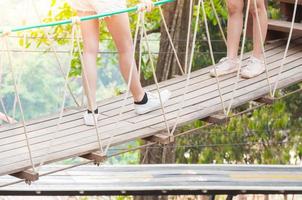 turista caminhando longe em uma de madeira suspensão ponte , Cruz para a de outros lado floresta foto