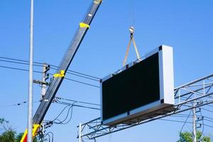 construção local guindaste é elevação uma conduziu tabuleta em branco Painel publicitário em azul céu fundo para Novo propaganda foto