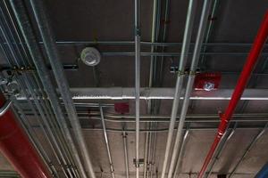 tubos do sistema sanitário e cabos elétricos instalados sob estrutura de concreto armado de laje plana no edifício tubos de ventilação em estacionamento subterrâneo foto