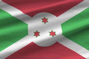 bandeira do burundi com grandes dobras acenando perto sob a luz do estúdio dentro de casa. os símbolos e cores oficiais no banner foto