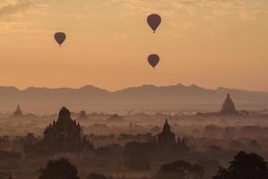 balões de ar quente sobrevoam as planícies de bagan durante o nascer do sol da manhã em mianmar. foto