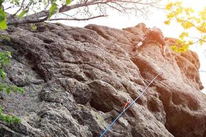 masculino alpinista, jovem alpinista escalada uma difícil rota em uma penhasco. alpinista sobe uma rochoso muro. com segurança corda em a Rocha foto