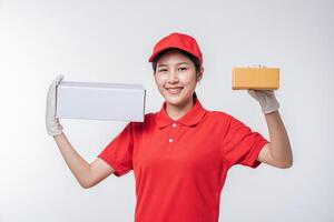 imagem do jovem entregador em uniforme de camiseta em branco de boné vermelho em pé com caixa de papelão branca vazia isolada no estúdio de fundo cinza claro foto