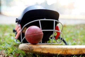 equipamento de críquete é uma bola de críquete, taco de críquete, capacete de críquete em um fundo de grama. foco suave e seletivo. foto