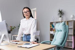 bem sucedido ásia o negócio mulher às local de trabalho dentro escritório olhando às Câmera, retrato do Forte líder foto