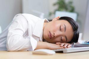 mulher escritório trabalhador cansado ásia dorme em a mesa, cansado demais dorme dentro a dia foto