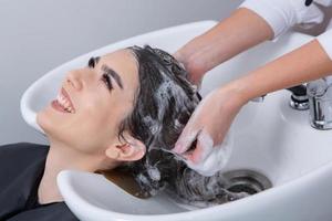 cabeleireiro profissional lavando o cabelo de jovem no salão de beleza. close-up do cabelo da mulher no salão de beleza, conceito de penteado foto