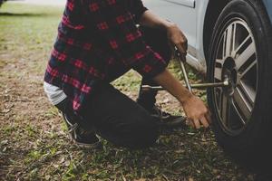 mulher jovem hippie verificando um pneu furado do carro foto