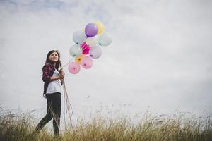 bela jovem hippie segurando balões coloridos ao ar livre foto