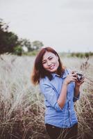 mulher feliz jovem hippie com câmera vintage em campo foto