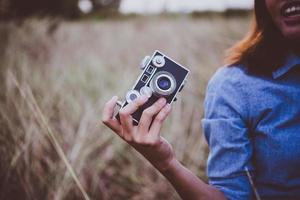 mulher feliz jovem hippie com câmera vintage em campo foto