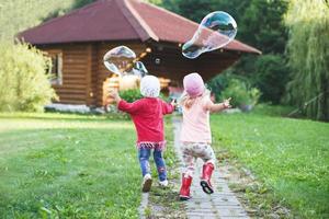 feliz meninas jogando com Sabonete bolhas ar livre. foto